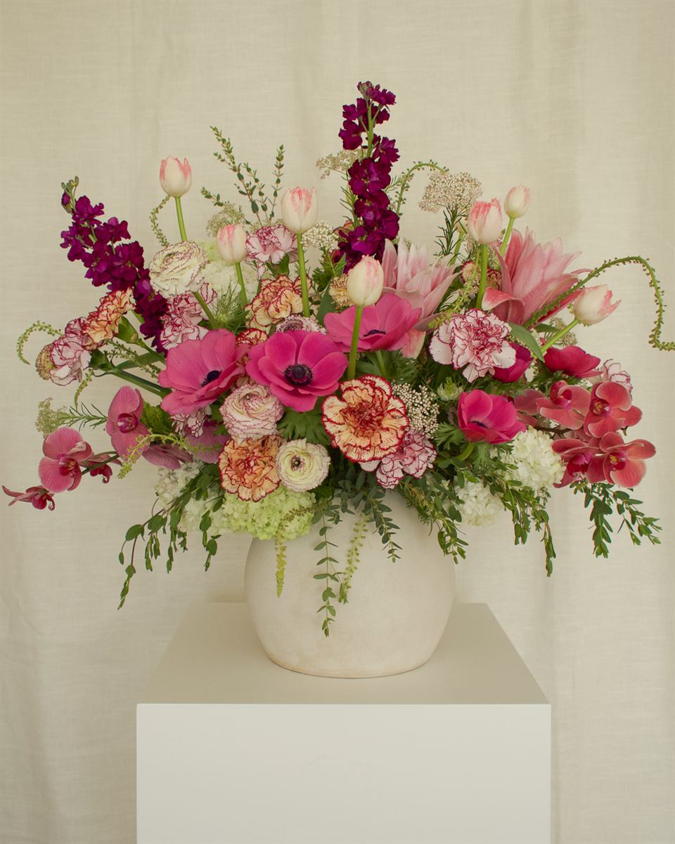 Pieza floral amplia en tonos fucsia y vino para decoración de evento